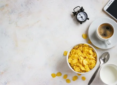 Corn flakes, coffee, alarm clock on a light background, breakfast Stock Photos