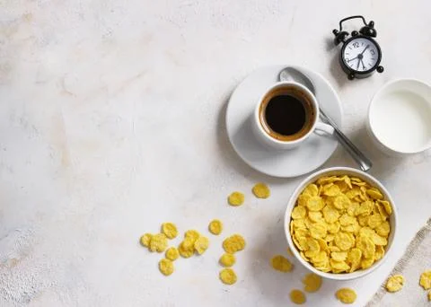 Corn flakes, coffee, alarm clock on a light background, breakfast Stock Photos