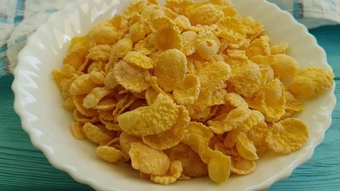 Corn flakes fall into a blue wooden plate, milk is poured, Stock Footage 88103956