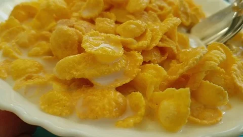 Corn flakes fall in a blue wooden plate, milk, spoon Stock Footage 88103975