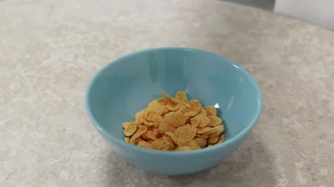 Corn flakes falling and filling a blue bowl Stock Footage 305138345