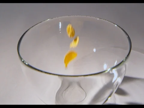 Corn flakes falling in a glass bowl, white background Stock Footage 74187176