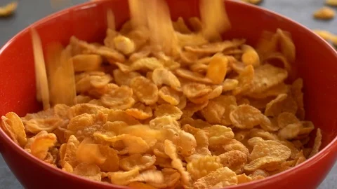 Corn flakes falling in a red bowl for breakfast, close up, slow motion Stock Footage 101164054