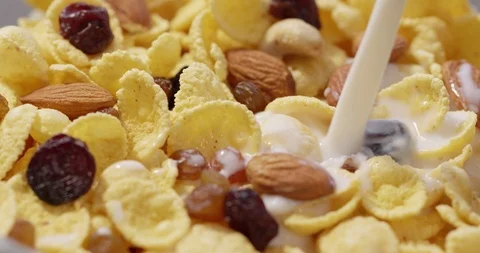 Corn Flakes with Nuts and Raisins pouring with Milk breakfast Stock Footage 125345410