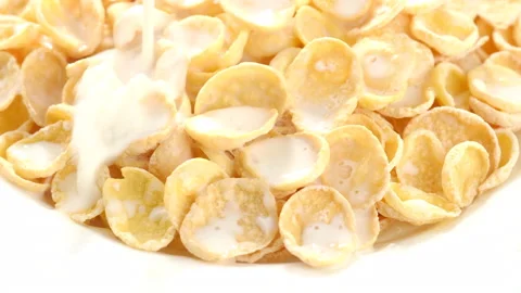 Corn flakes pouring milk in white plate rotating, closeup. top view 動画素材 132042180