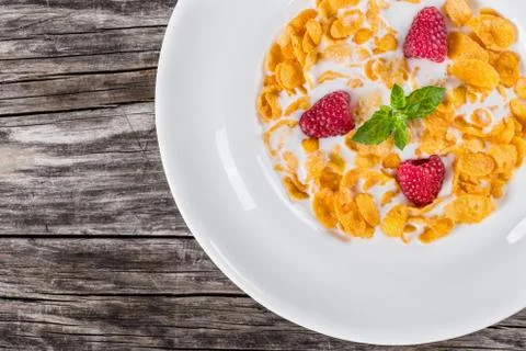 Corn flakes with raspberry and cold milk decorated with mint Stock Photos