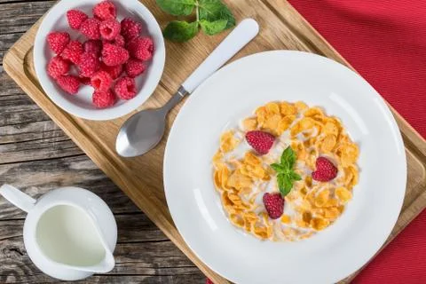 Corn flakes with raspberry and milk in plate Stock Photos