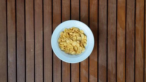 Corn flakes in a white plate in the middle on a wooden background for breakfast Stock Photos