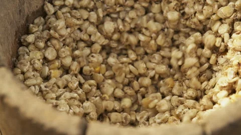 Corn grains are ground with a pestle in a mortar. Close-up Stock Footage 257683519