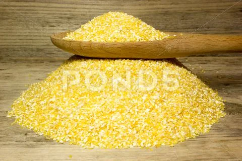 Corn Grits And Wooden Spoon On Wooden Background