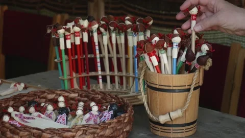 Corn husk figurines in basket, container, and stand with hand adding pencil Stock Footage 313792938