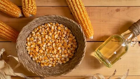 Corn kernels in a basket with corn cobs and oil on wood Stock Photos