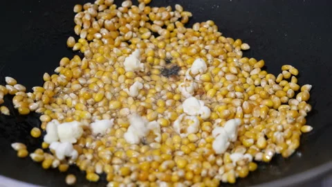 Corn kernels exploding in a pan and turning into popcorn. Making popcorn at home Stock Footage 235299799