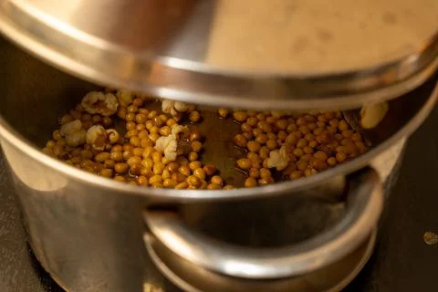 From corn kernels to popcorn in the kitchen pot Stock Photos