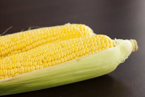 Corn lying on a wooden table Stock Photos