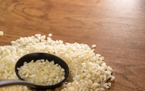 Corn for preparing hominy dish in shell on woody background Stock Photos