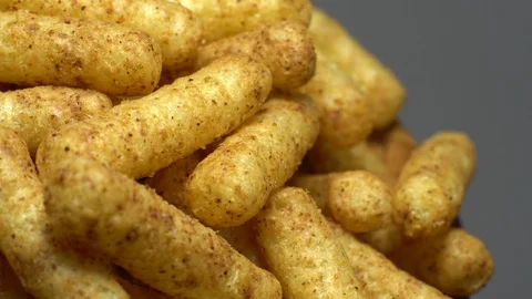 Corn puffs. Rotation. Close up. Puffcorn with peanut flavor. Grey background. Stock Footage 101298155