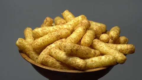 Corn puffs. Rotation. Close up. Puffcorn with peanut flavor. Grey background. 動画素材 101298247