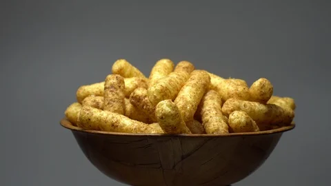Corn puffs. Rotation. Close up. Puffcorn with peanut flavor. Grey background. Stock Footage 101298393