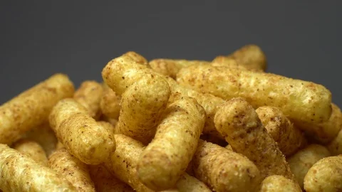 Corn puffs. Rotation. Close up. Puffcorn with peanut flavor. Grey background. Stock Footage 101298401