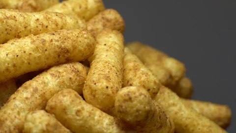 Corn puffs. Rotation. Close up. Puffcorn with peanut flavor. Grey background. Stock Footage 101298454