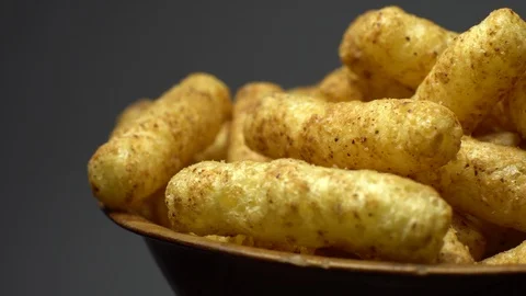 Corn puffs. Rotation. Close up. Puffcorn with peanut flavor. Grey background. Stock Footage 101299218