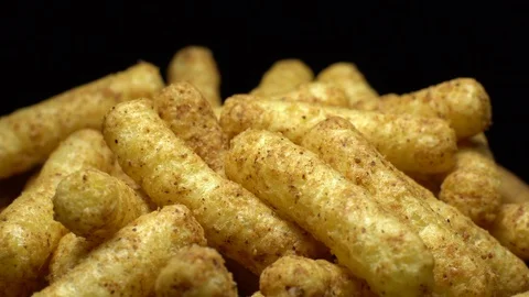 Corn puffs. Rotation. Close up.  Puffcorn with peanut flavor. Black background. Stock Footage 101302370