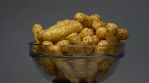 Corn puffs. Rotation. Close up. Puffcorn with peanut flavor. Grey background. Stock Footage 101303743
