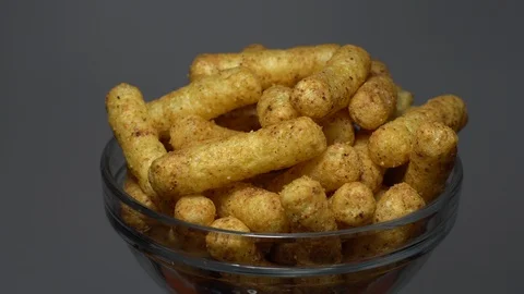 Corn puffs. Rotation. Close up. Puffcorn with peanut flavor. Grey background. Stock Footage 101303828