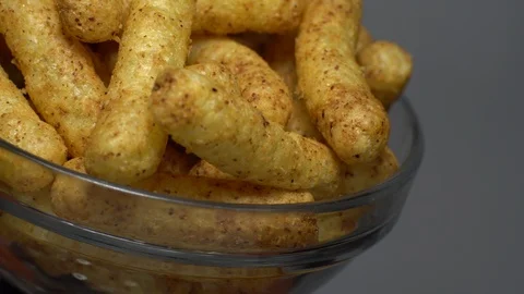 Corn puffs. Rotation. Close up. Puffcorn with peanut flavor. Grey background. Stock Footage 101303862
