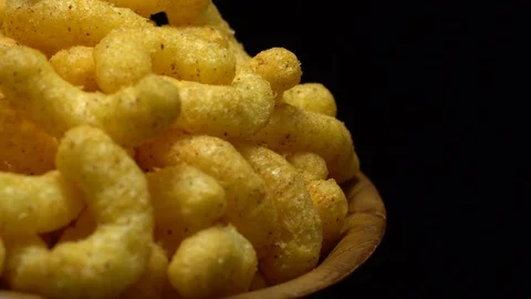 Corn puffs. Rotation. Close up.  Puffcorn with peanut flavor. Black background. Stock Footage 101313372
