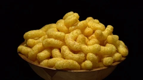 Corn puffs. Rotation. Close up.  Puffcorn with peanut flavor. Black background. Stock Footage 101313413
