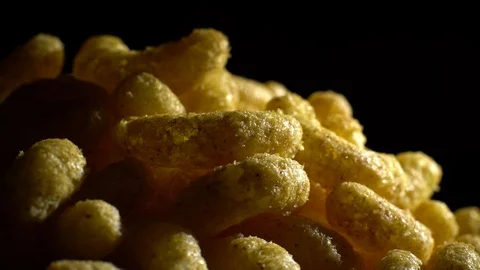 Corn puffs. Rotation. Close up.  Puffcorn with peanut flavor. Black background. Stock Footage 101313440