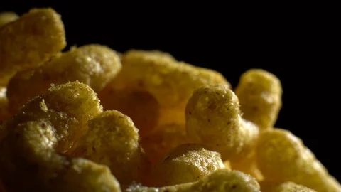 Corn puffs. Rotation. Close up.  Puffcorn with peanut flavor. Black background. Stock Footage 101313590