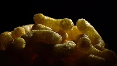 Corn puffs. Rotation. Close up.  Puffcorn with peanut flavor. Black background. Stock Footage 101313631