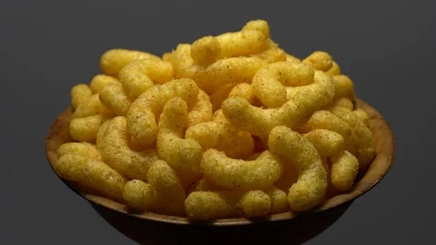 Corn puffs. Rotation. Close up. Puffcorn with peanut flavor. Grey background. Stock Footage 101313746