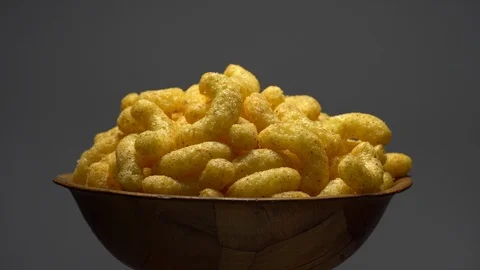 Corn puffs. Rotation. Close up. Puffcorn with peanut flavor. Grey background. Stock Footage 101313765