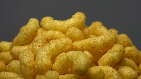 Corn puffs. Rotation. Close up. Puffcorn with peanut flavor. Grey background. Stock Footage 101313803