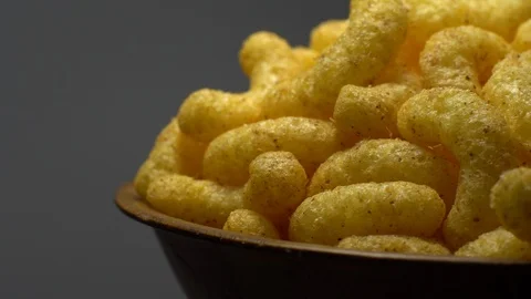 Corn puffs. Rotation. Close up. Puffcorn with peanut flavor. Grey background. Stock Footage 101313831