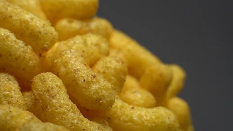 Corn puffs. Rotation. Close up. Puffcorn with peanut flavor. Grey background. Stock Footage 101313909
