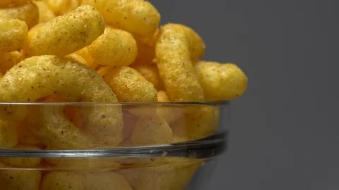 Corn puffs. Rotation. Close up. Puffcorn with peanut flavor. Grey background. Stock Footage 101313949