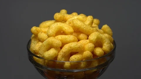 Corn puffs. Rotation. Close up. Puffcorn with peanut flavor. Grey background. Stock Footage 101313981