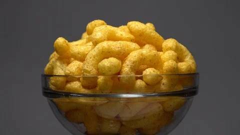 Corn puffs. Rotation. Close up. Puffcorn with peanut flavor. Grey background. Stock Footage 101313996