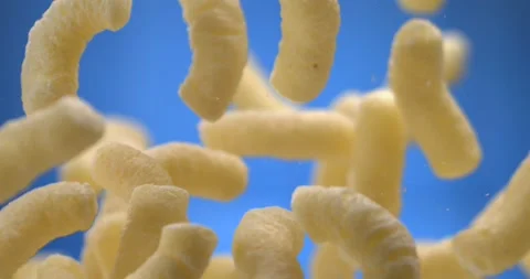 Corn sticks cheese puffs floating in the air on blue background slow motion Stock Footage 344849673
