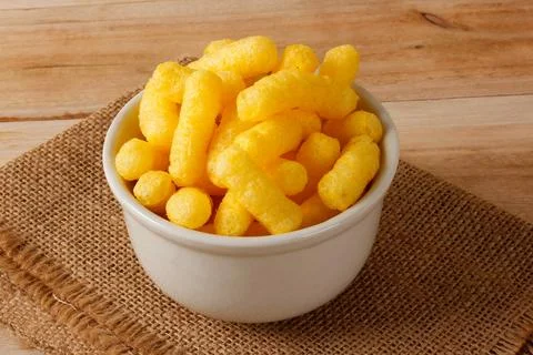 Corn sticks in a small white bowl on a jute cloth and a wooden table Stock Photos