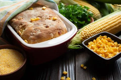 Cornbread in ceramic baking dish on wooden kitchen table Stock Photos