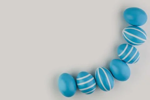 Corner border of blue striped Easter eggs over a light background. Stock Photos