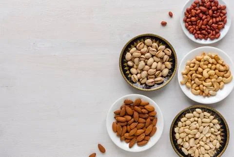 Corner border of fresh nuts in individual bowls Stock Photos