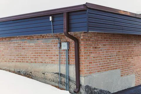 Corner of brick building with brown gutter and siding Stock Photos