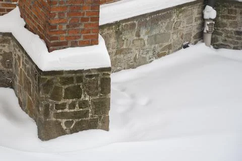 A corner of a building featuring a brick pillar and a stone foundation, 스톡 사진